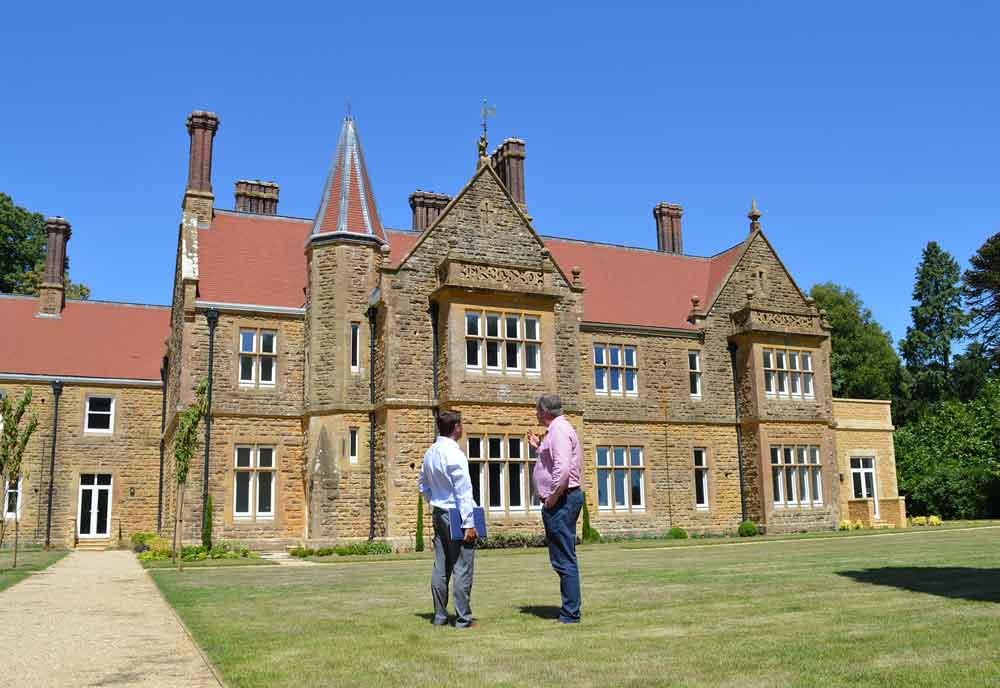 two men stood discussing large brick property