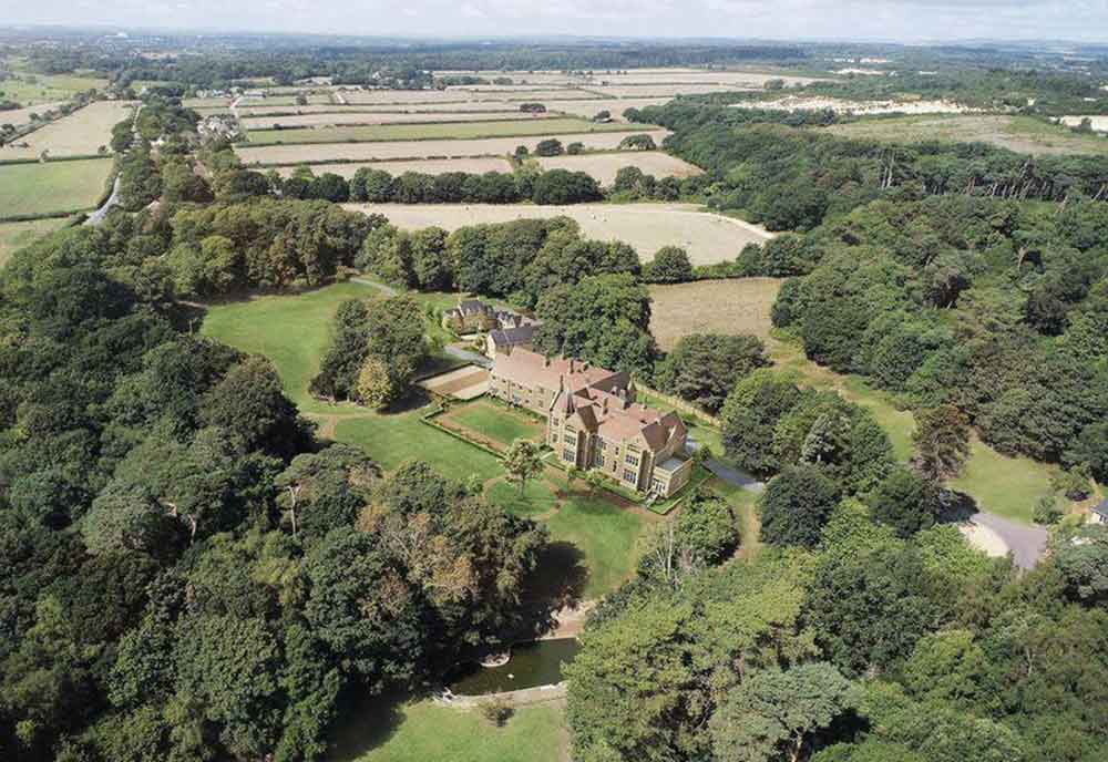 aerial view of a group of houses surrounded be forest and fields