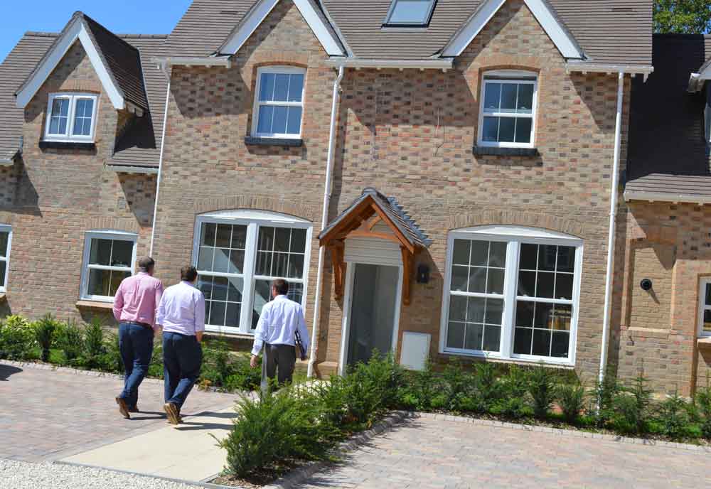3 people walking towards a newly built home
