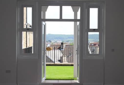 view through open doors, onto a balcony overlooking rooftops